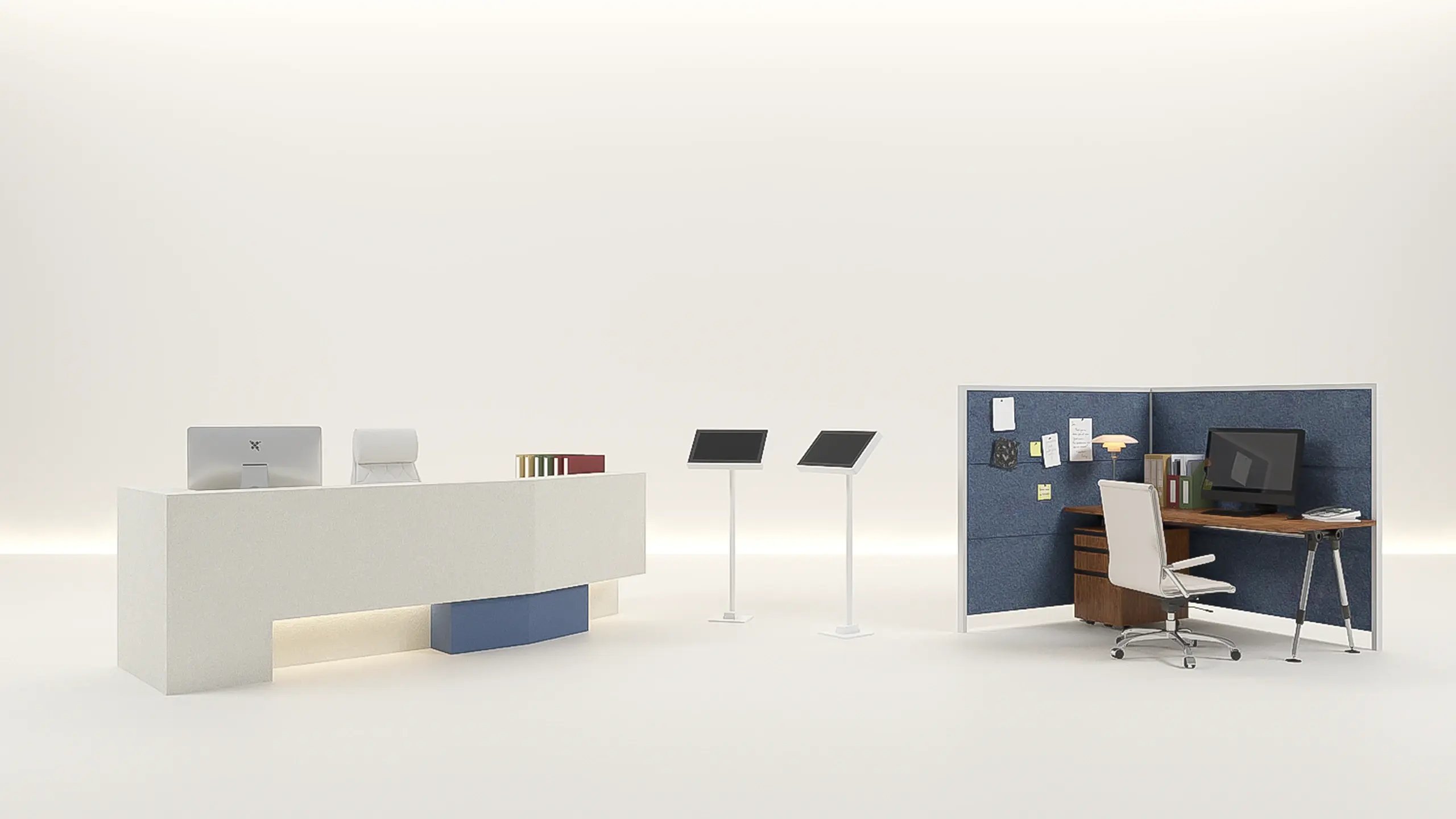 A reception desk with a monitor, two self-service check-in kiosks and a workstation cubicle, arranged on an open studio floor.