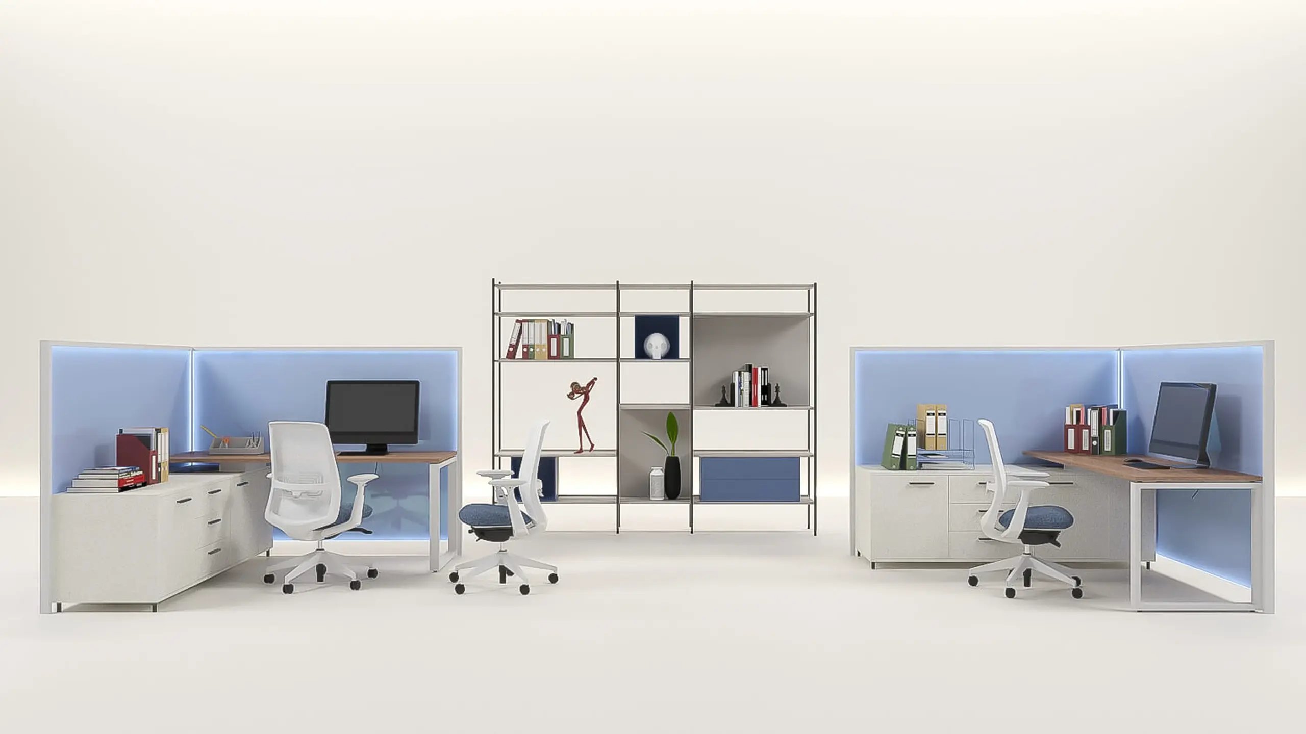 Two partitioned administrative workstations with monitors, storage credenzas and task chairs, flanking an open shelving unit of binders, files and plants, on an open studio floor.