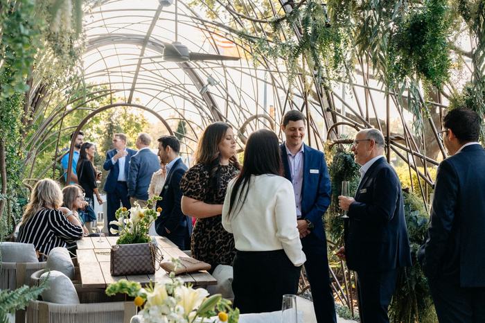 Guests gathering under the glasshouse arches before the Houston dinner