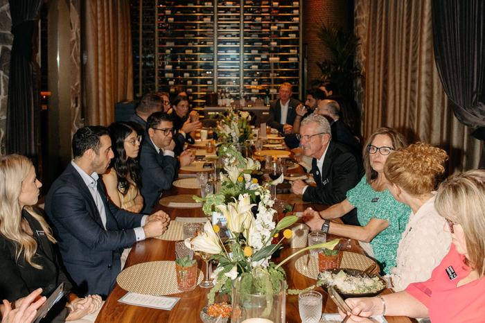 The full table seated for dinner in Houston, in conversation
