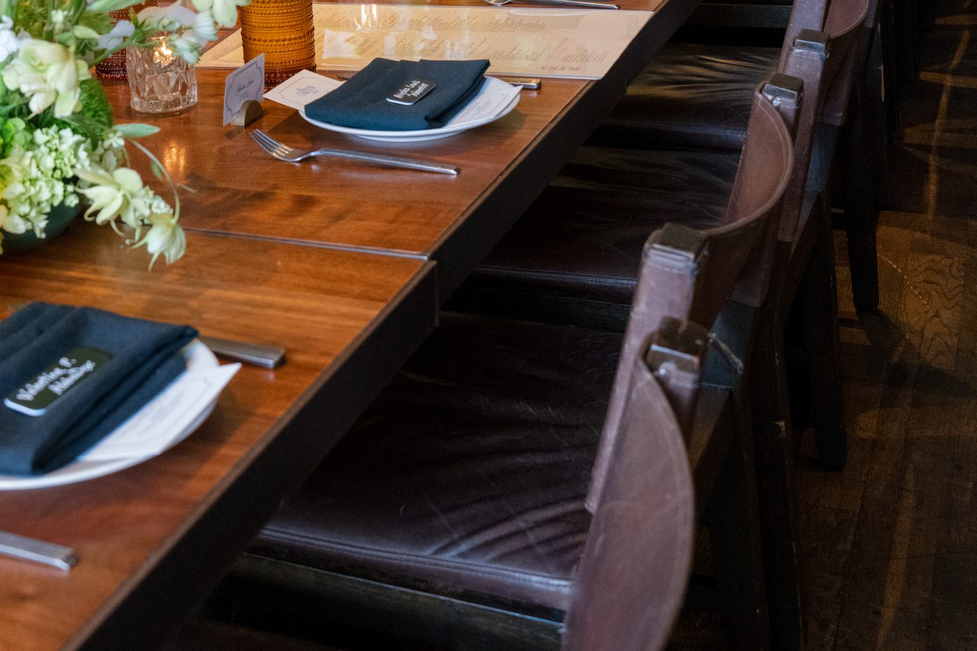 One long CareFlow Club table set end to end with printed dinner menus, navy napkins and white florals