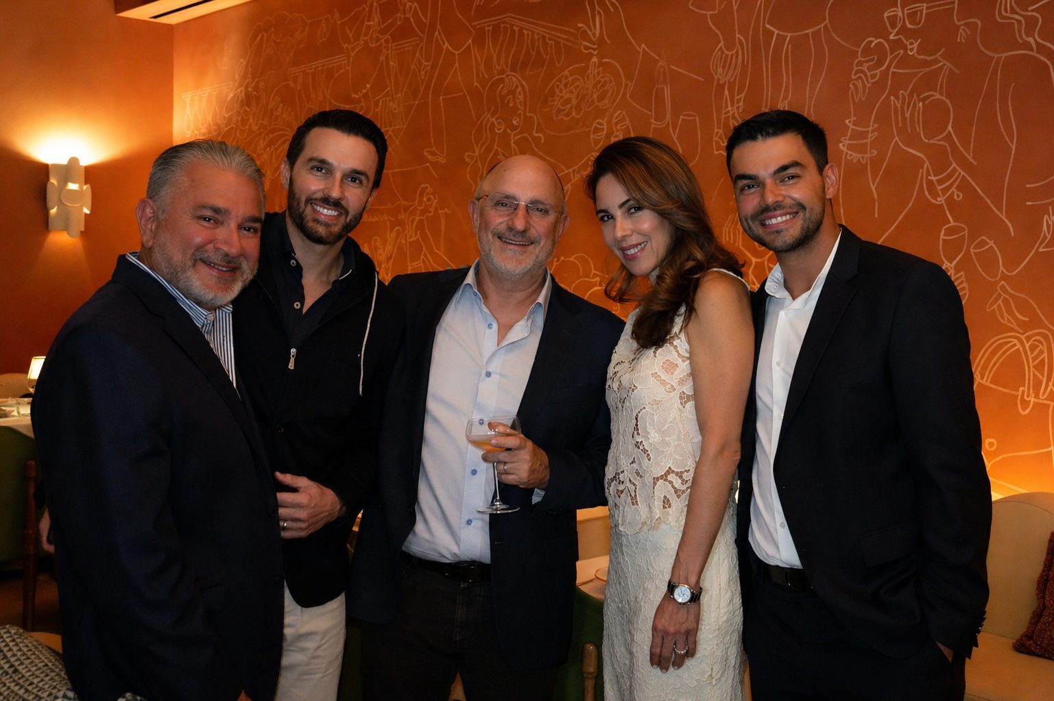 Five guests together against the terracotta mural at the Miami dinner